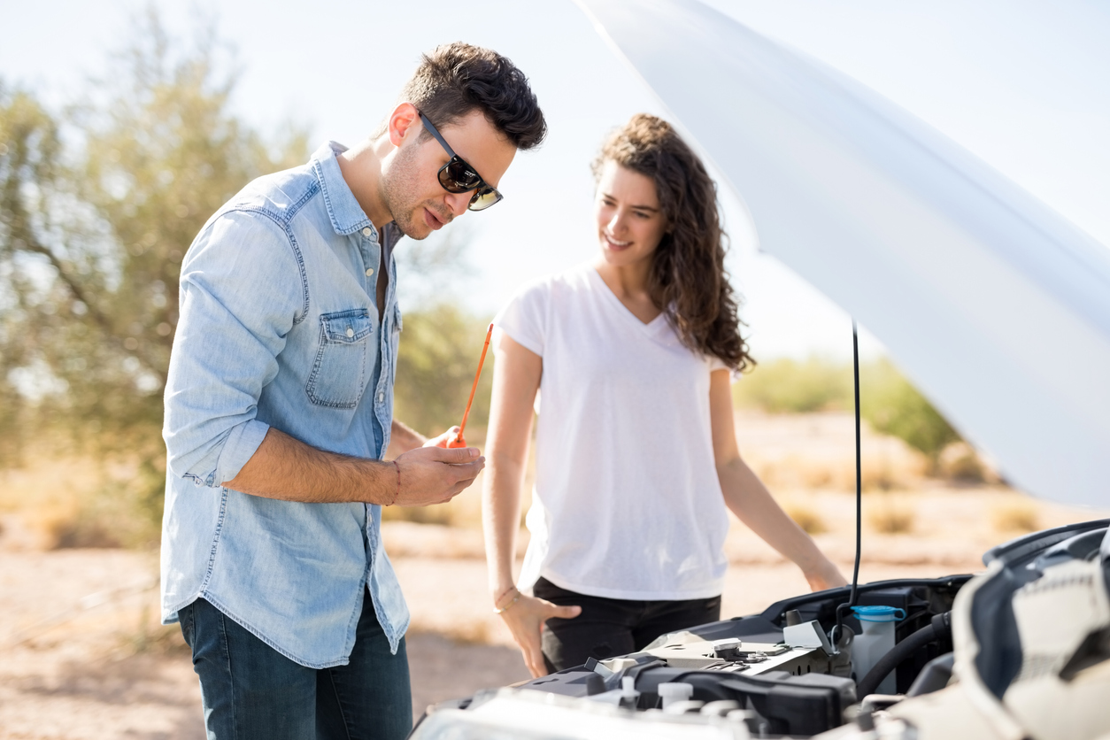 Man and women completing checks inside bonnet of car 