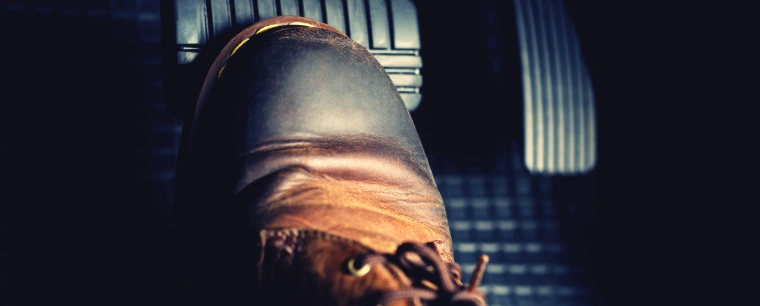 A boot tip pressed on the car brake pedal.