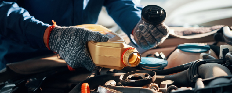 Worker pouring oil into car