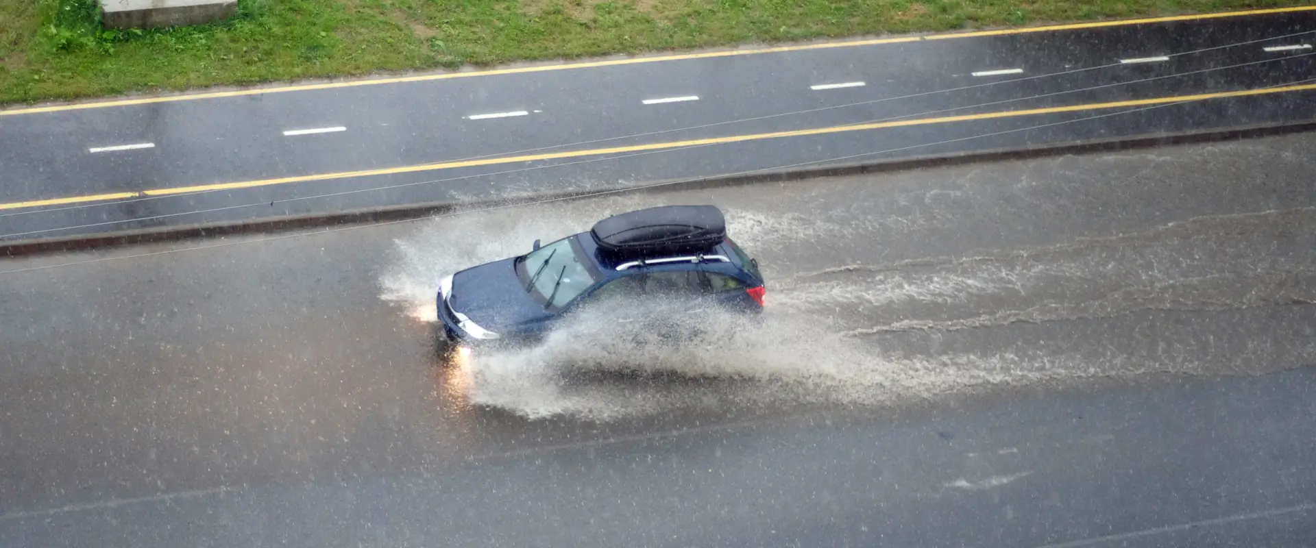 A car in heavy rain driving through a puddle