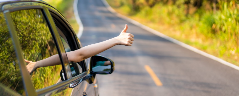 Person putting thumb out the window of vehicle