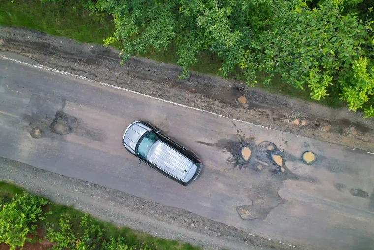 An aerial view of a car that has skidded on the road because of potholes.