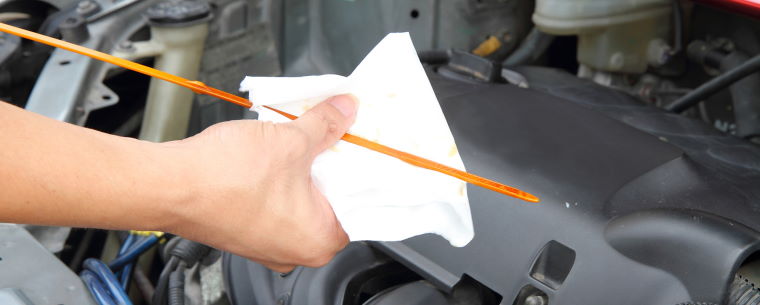 Technician checking engine oil level with a dipstick