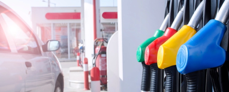 Four fuel pumps with unleaded petrol, premium petrol, super unleaded petrol, and diesel sit waiting for use near a car