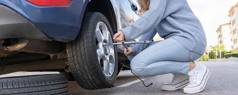 Woman replacing tyre on a correctly jacked up car.