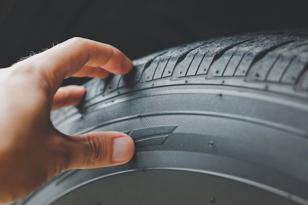 A hand inspects the texture of a tyre tread pattern.