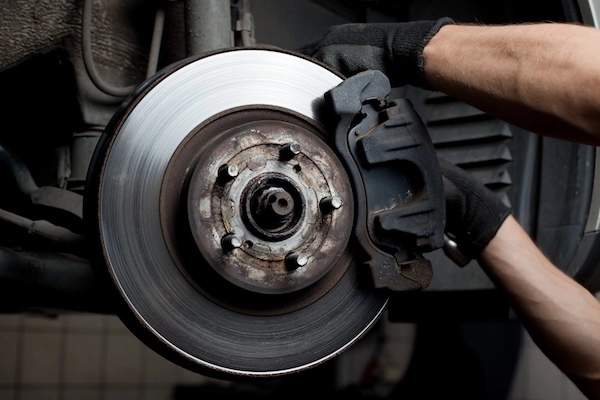 Technician repairing brake pads on a vehicle.