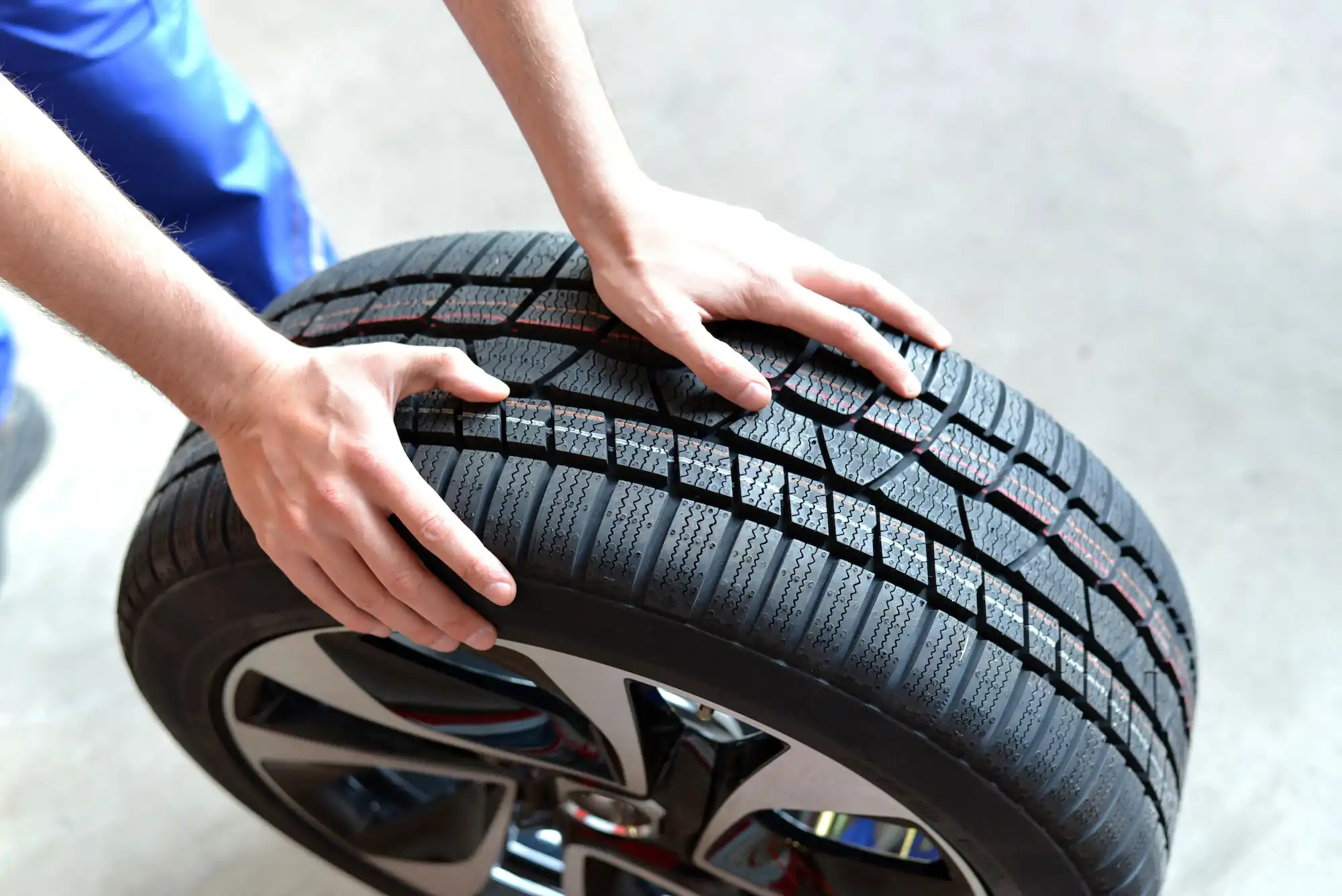 A mechanic rolling a tyre along the floor.