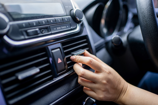 A person adjusts the vent positioning on their car's air con.