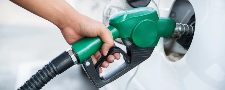Person holding a green petrol pump into a white car.