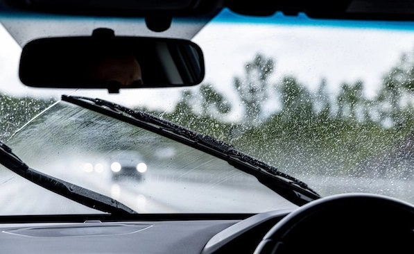Wipers clear rain from a windscreen.