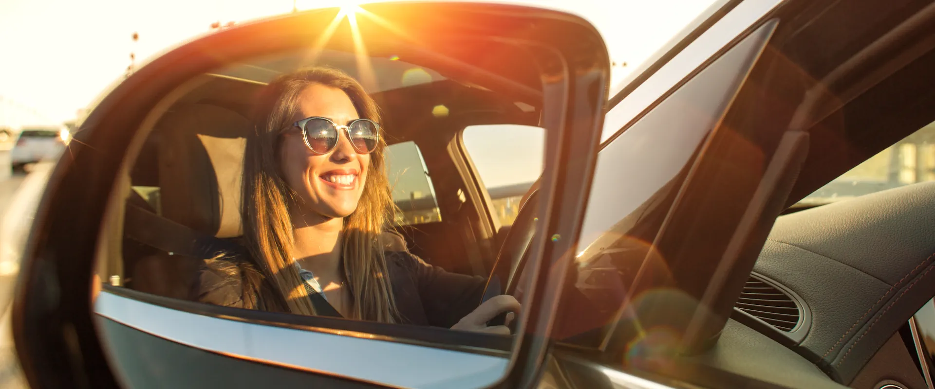 Female driver with sunglasses in a wing mirror