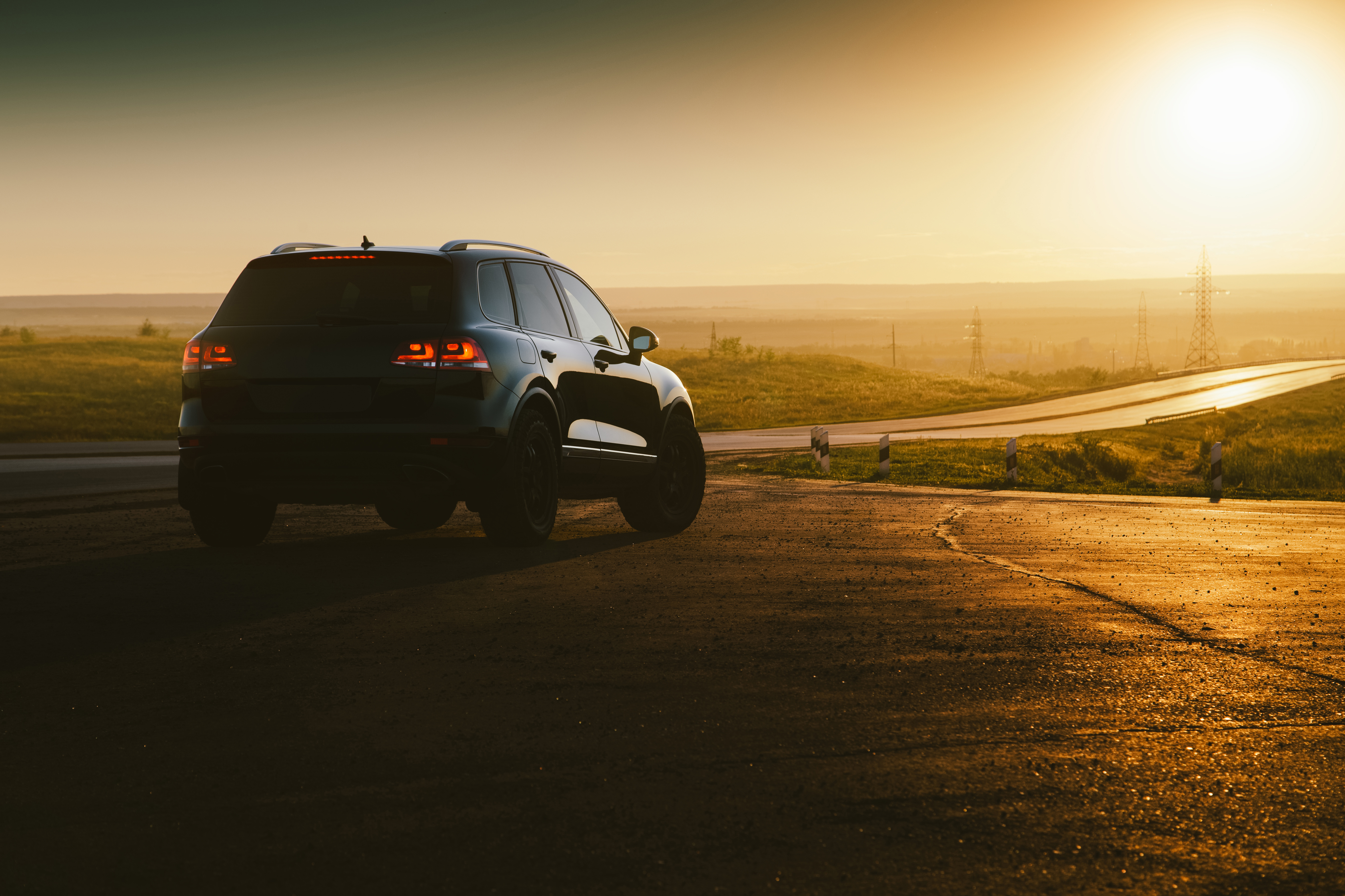 A sleek black SUV overlooks a motorway at sunset.