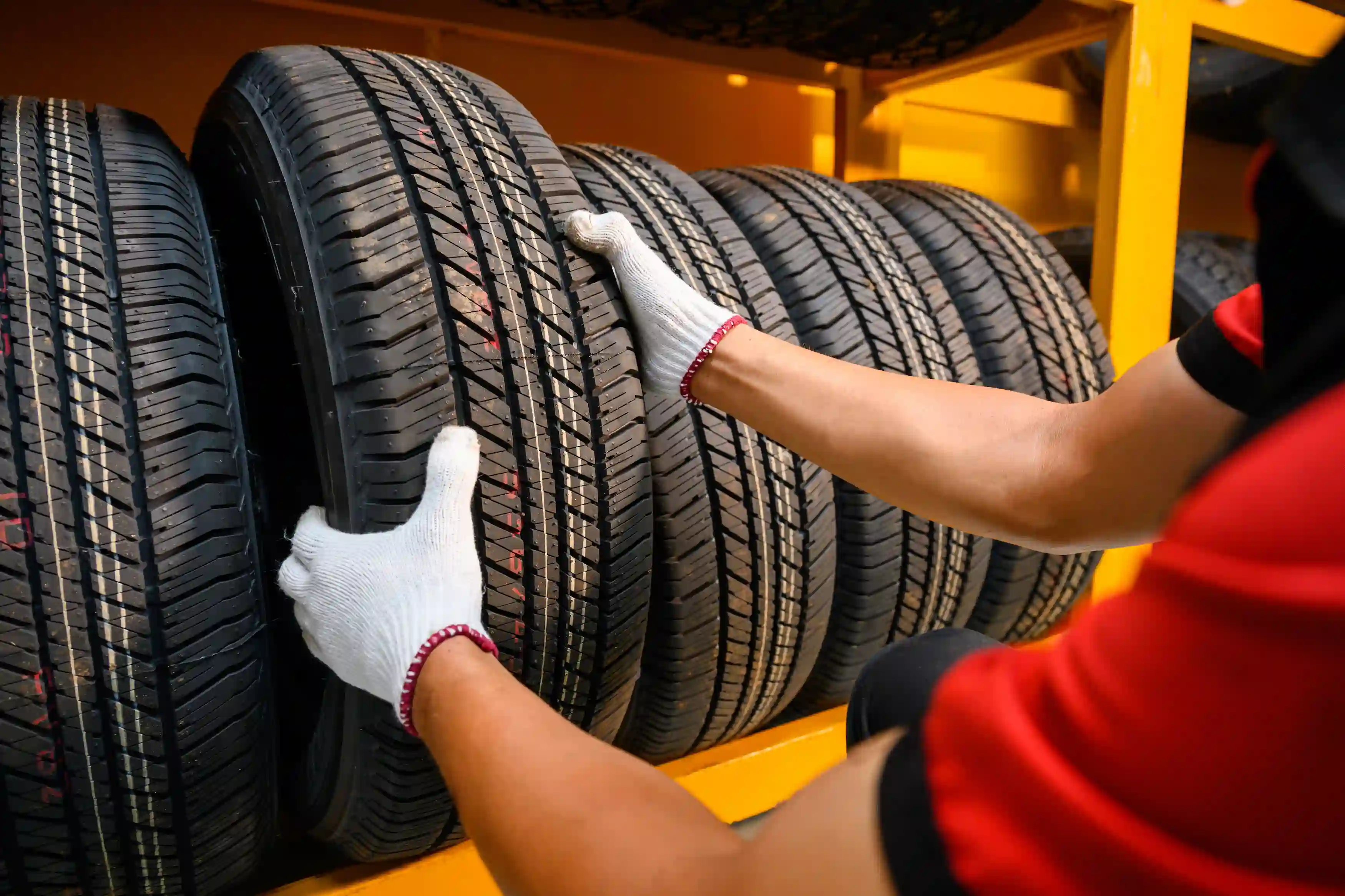 A person pulling a tyre off of a rack in tyre storage.