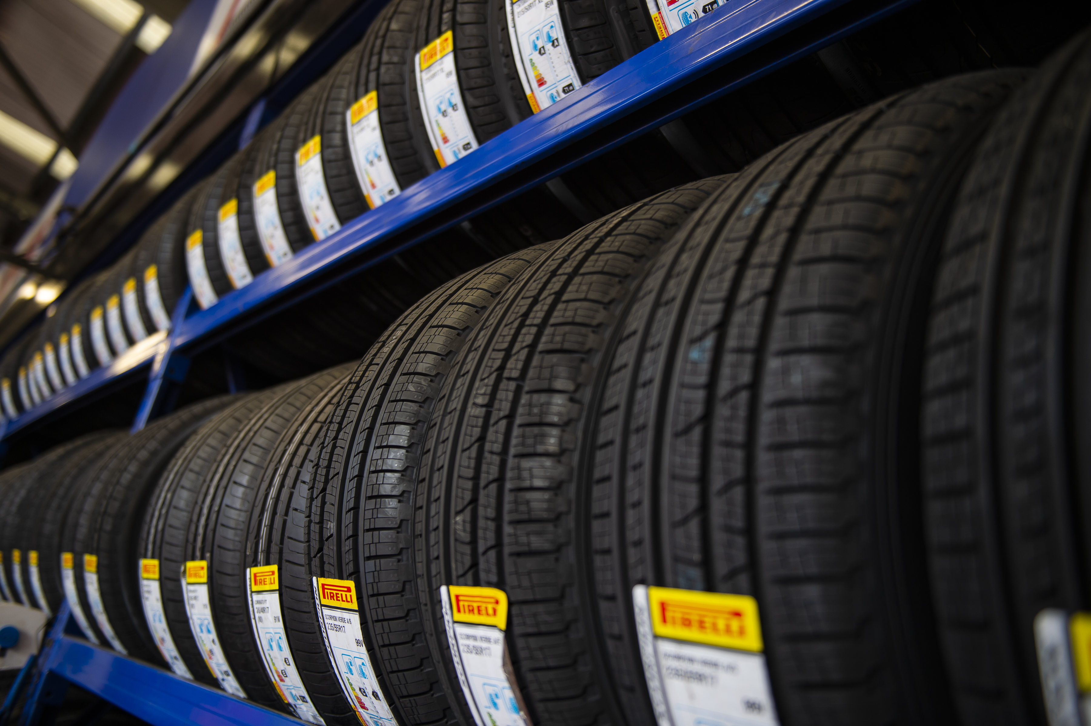 Racks of tyres with tyre marking stickers on in a garage.