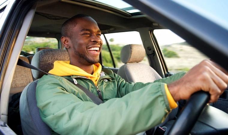 A young man happy to be driving in pleasant morning sunlight.